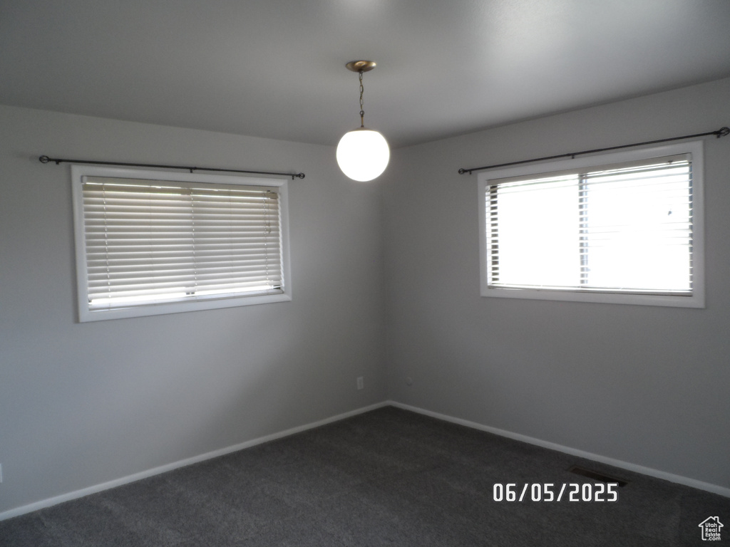 Spare room with baseboards and dark colored carpet