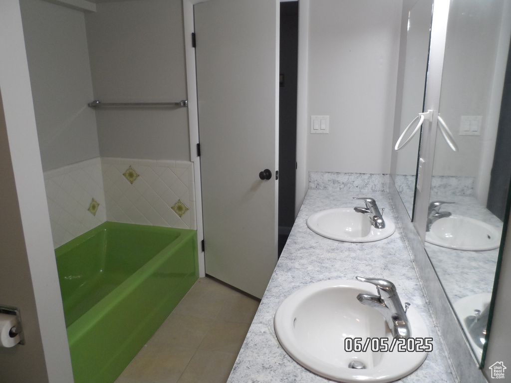 Full bath featuring a tub, double vanity, and tile patterned flooring
