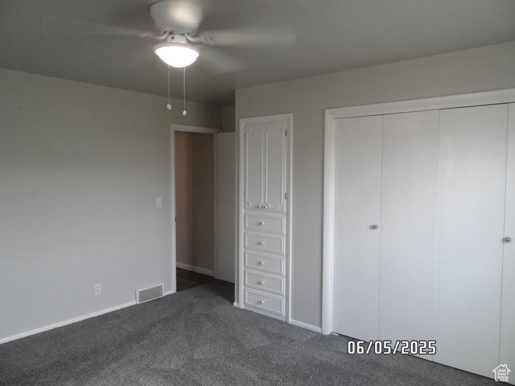 Unfurnished bedroom with dark carpet, a closet, baseboards, and ceiling fan