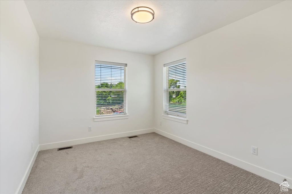 Empty room featuring baseboards and light colored carpet