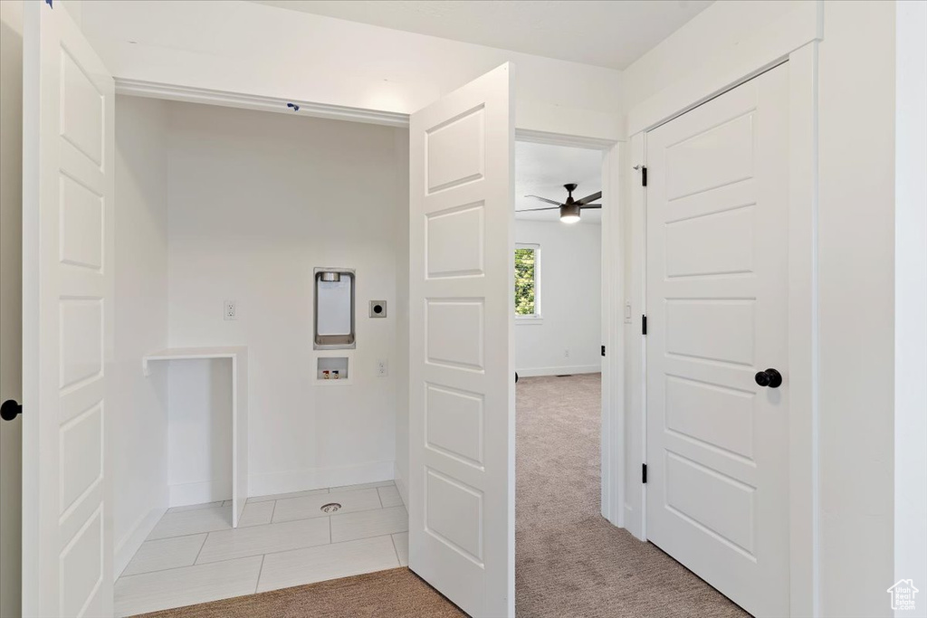 Hallway with light carpet, baseboards, and light tile patterned floors