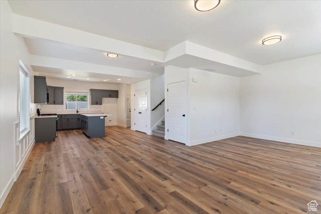 Unfurnished living room with wood finished floors, stairs, baseboards, and a sink
