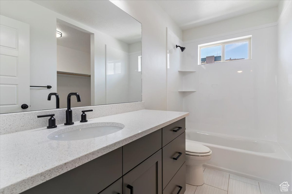 Full bathroom featuring toilet, vanity, washtub / shower combination, and tile patterned flooring