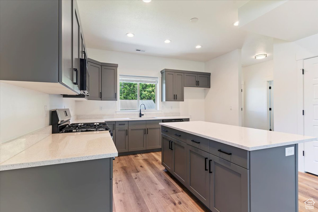 Kitchen featuring gray cabinets, stainless steel gas range oven, light wood-type flooring, and recessed lighting