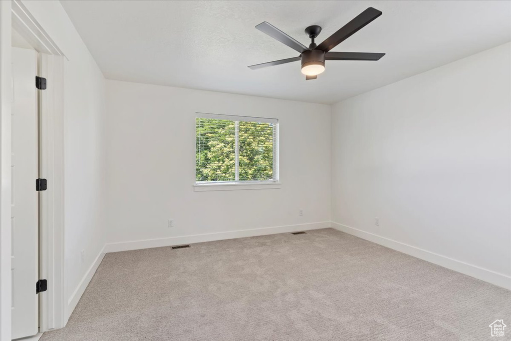 Unfurnished room with baseboards, light colored carpet, and ceiling fan
