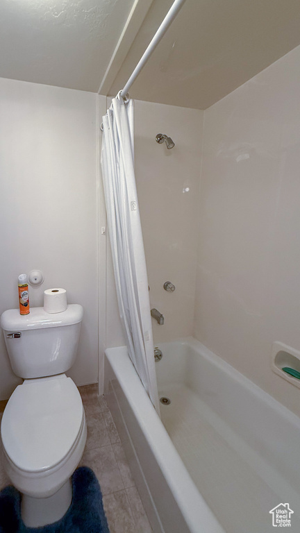 Bathroom with toilet, shower / tub combo, and tile patterned flooring