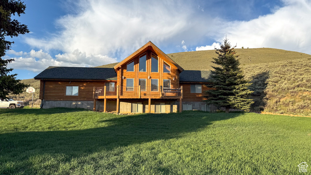 Back of house featuring log siding, a yard, a deck, and roof with shingles