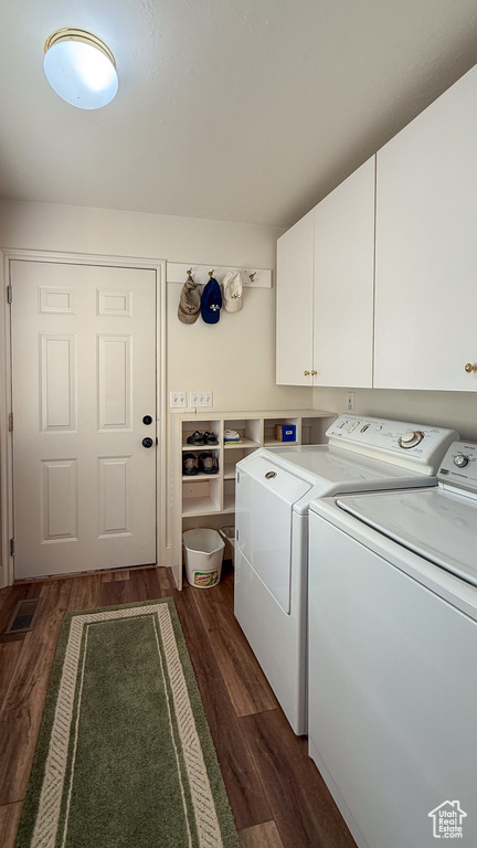 Washroom featuring cabinet space, washer and clothes dryer, and dark wood-type flooring