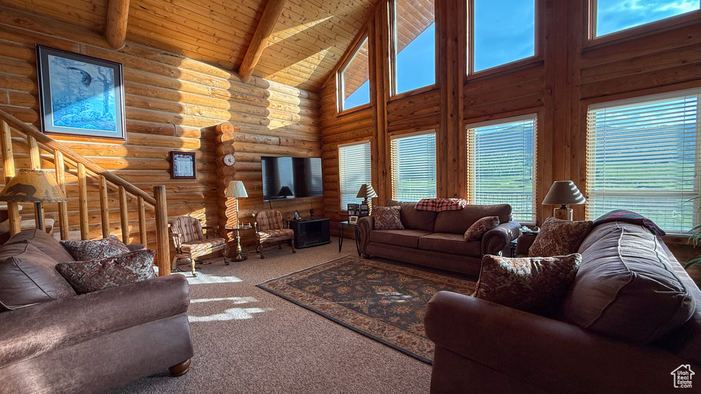 Carpeted living room with high vaulted ceiling, log walls, and wooden ceiling with exposed beams