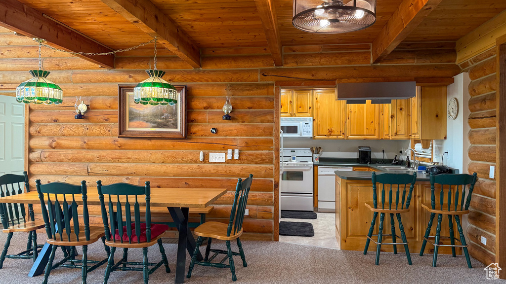 Kitchen featuring white appliances, wooden ceiling with exposed beams, log walls, dark countertops, and light carpet