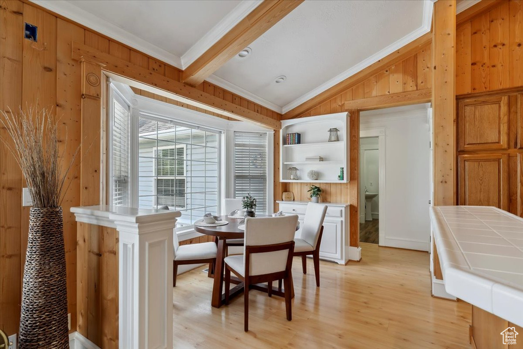 Dining space featuring wooden walls, ornamental molding, and light wood finished floors