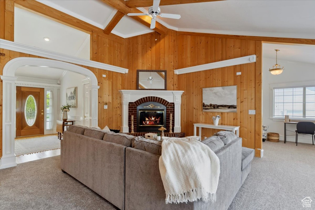 Living area featuring a ceiling fan, wooden walls, plenty of natural light, arched walkways, and carpet