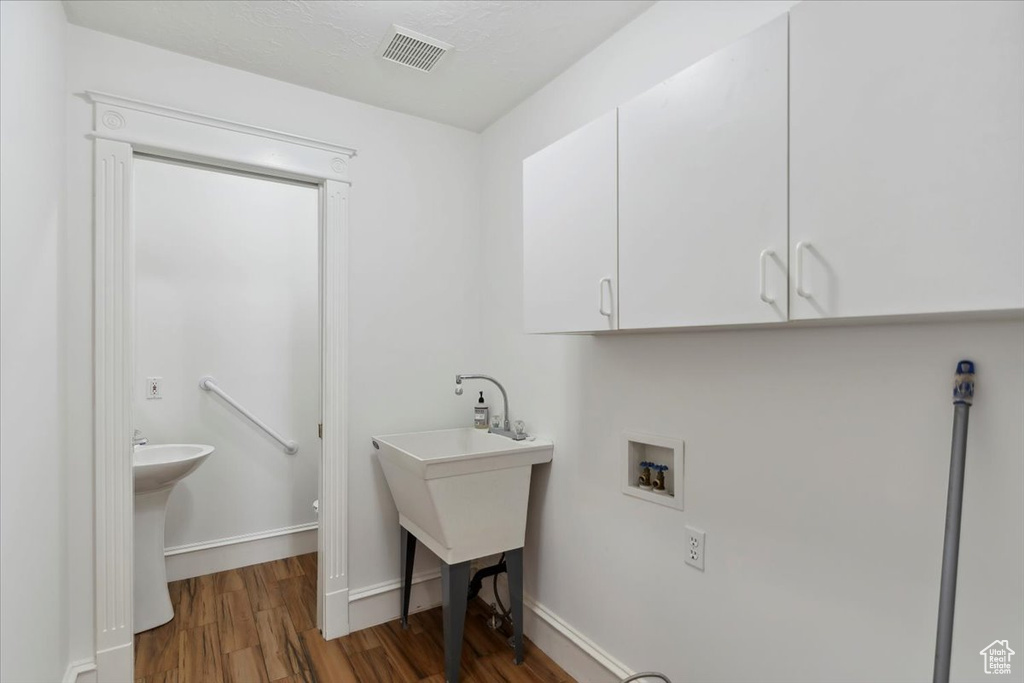 Laundry room featuring washer hookup, wood finished floors, cabinet space, and baseboards