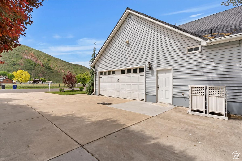 View of property exterior with a mountain view, concrete driveway, and an attached garage