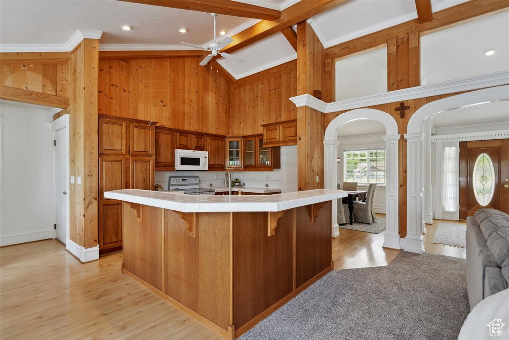 Kitchen with white appliances, tile countertops, ornate columns, crown molding, and ceiling fan