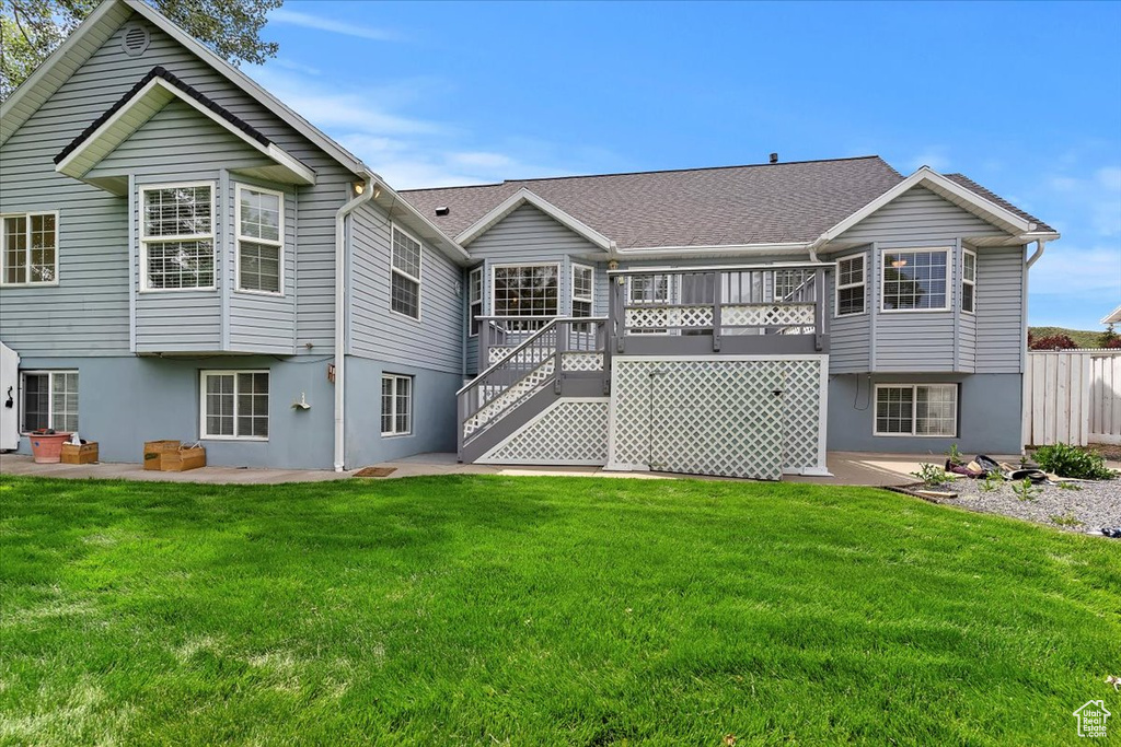 Back of house with stucco siding, a lawn, stairs, and a patio