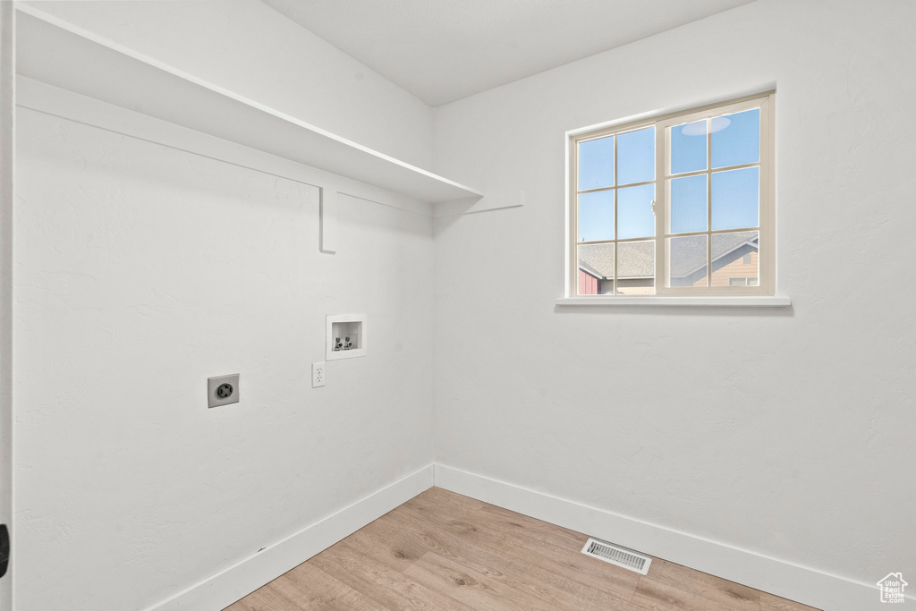 Laundry area featuring electric dryer hookup, washer hookup, light wood finished floors, and baseboards