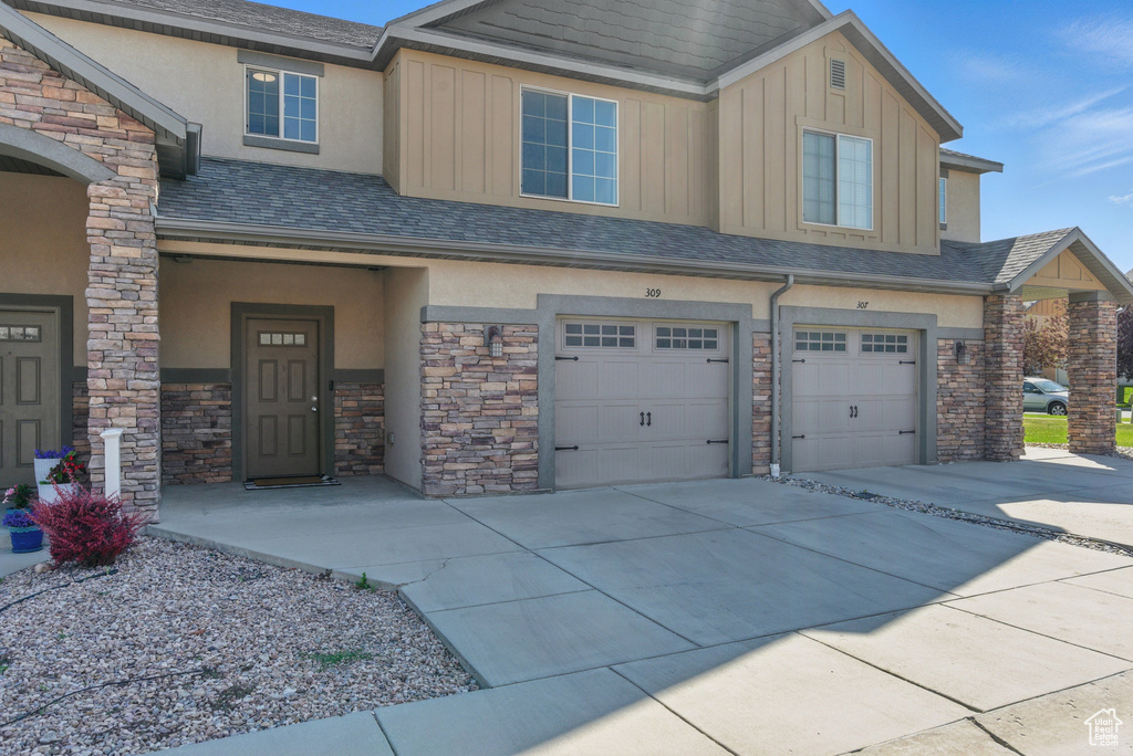 View of front of property with stone siding, stucco siding, and a garage
