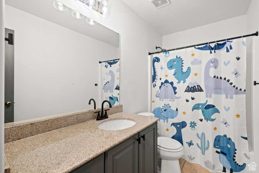 Bathroom featuring vanity, toilet, a shower with curtain, and tile patterned flooring