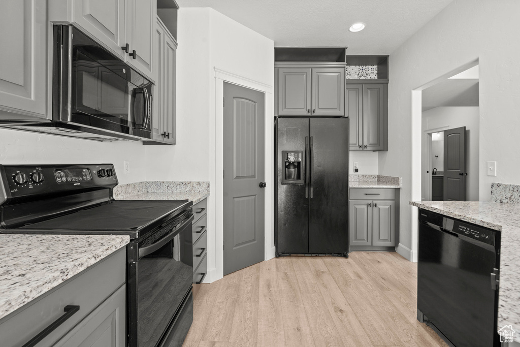 Kitchen featuring black appliances, gray cabinetry, light wood finished floors, and recessed lighting