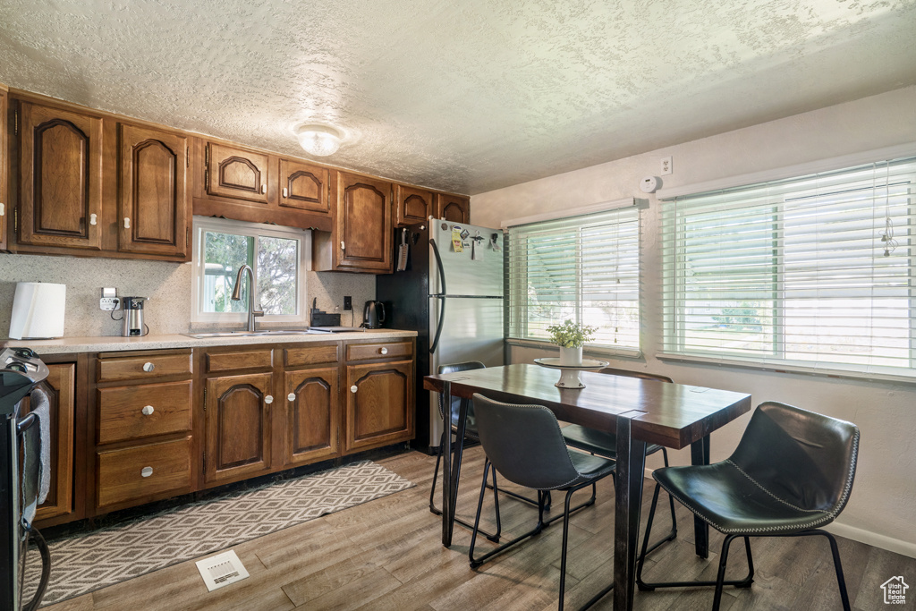 Kitchen featuring a sink, light wood-type flooring, stainless steel appliances, light countertops, and a textured ceiling