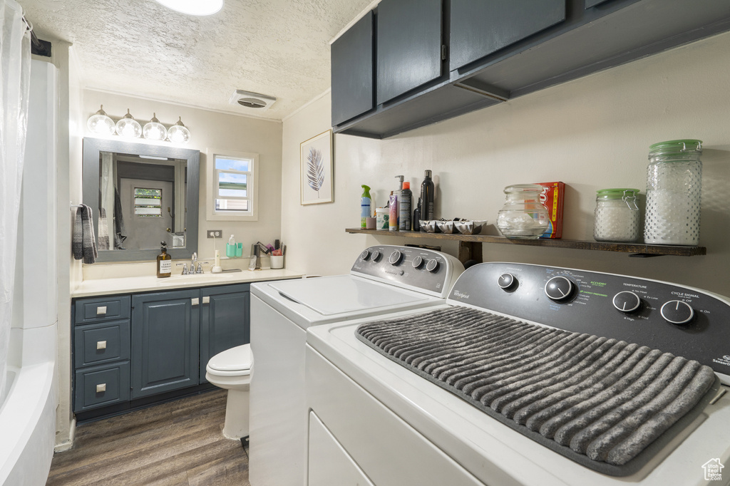 Washroom featuring independent washer and dryer, dark wood-type flooring, and a textured ceiling