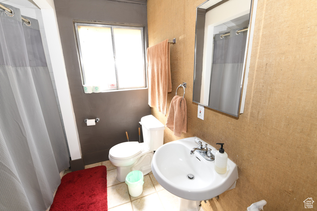 Bathroom featuring a sink, toilet, a shower with curtain, and tile patterned flooring