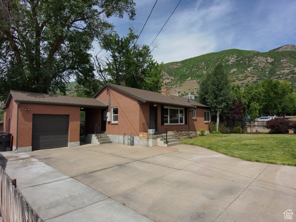 View of front of house featuring a garage, a mountain view, driveway, and brick siding