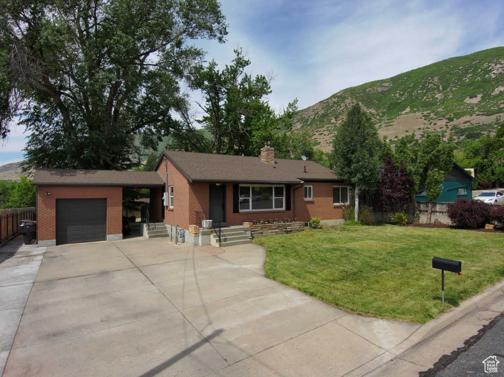 Single story home with brick siding, an attached garage, a mountain view, driveway, and a chimney