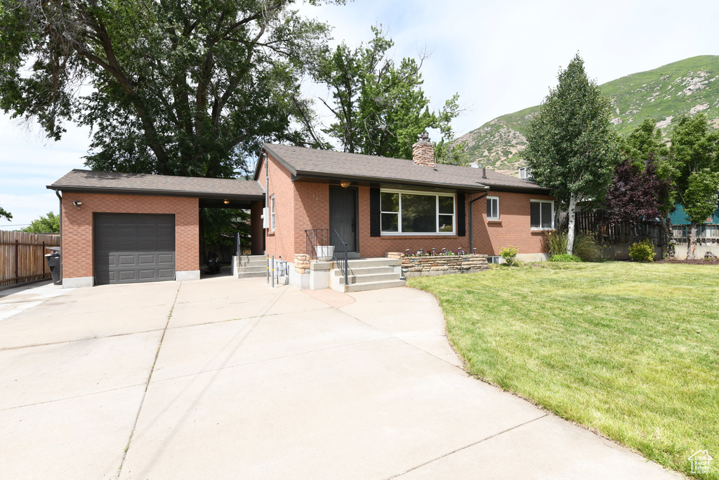 Single story home featuring a garage, concrete driveway, brick siding, a mountain view, and a chimney