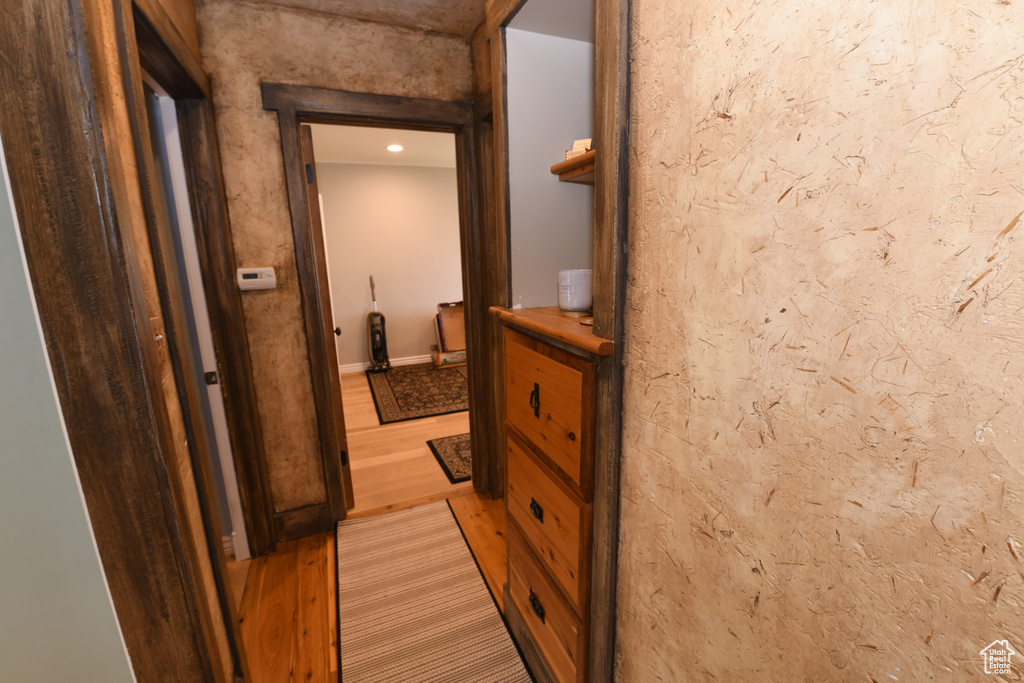 Corridor with light wood-type flooring and recessed lighting