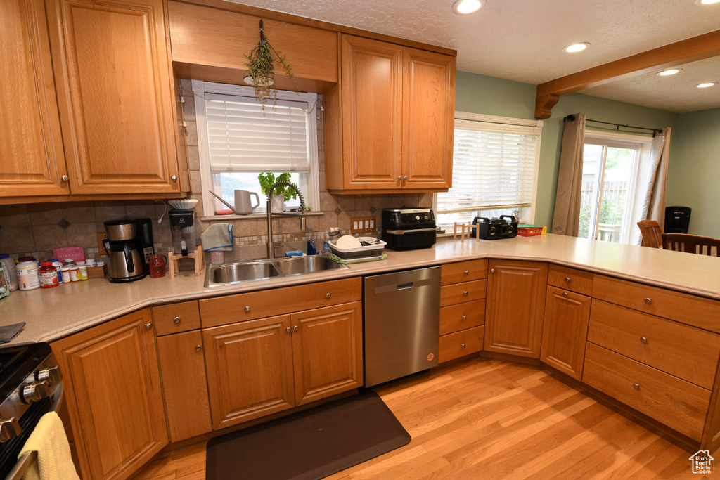 Kitchen featuring appliances with stainless steel finishes, a sink, tasteful backsplash, light wood finished floors, and recessed lighting
