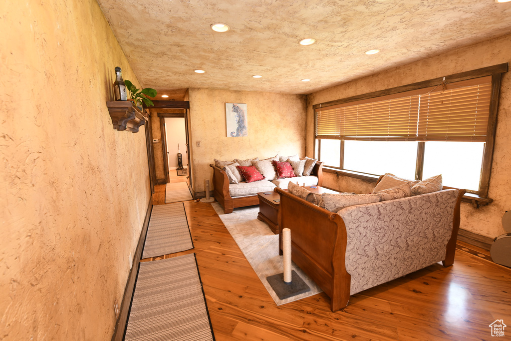 Living area with a textured wall, light wood finished floors, and recessed lighting