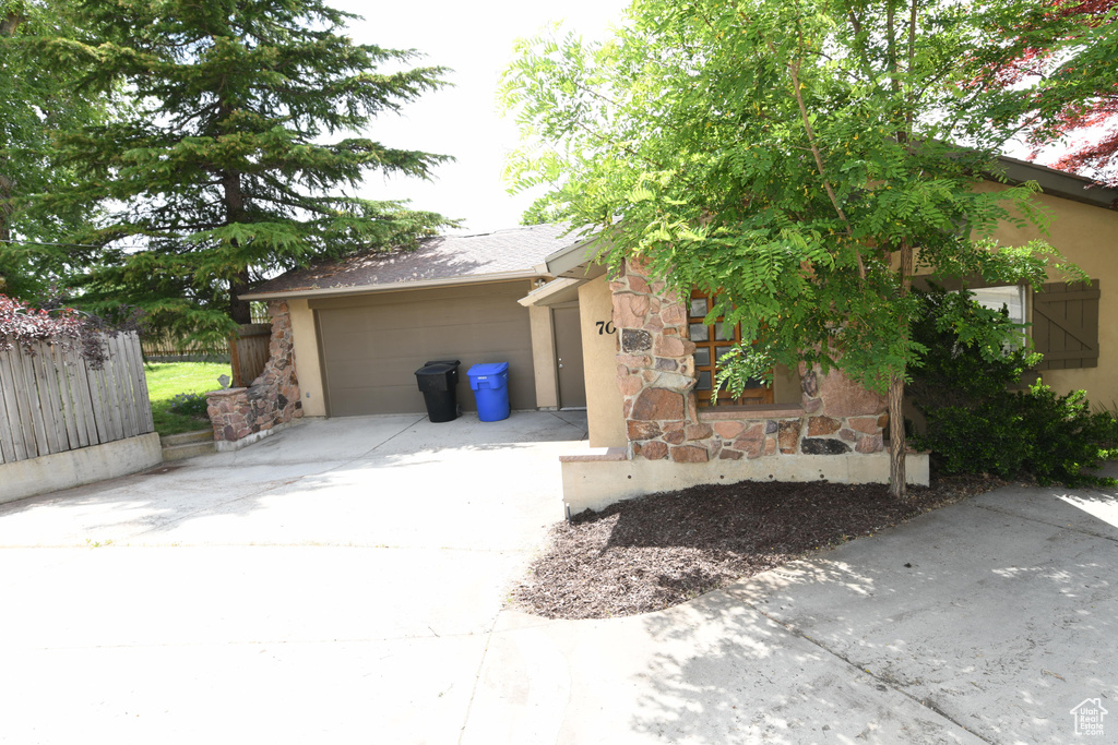 View of front facade featuring driveway, stone siding, a garage, and stucco siding