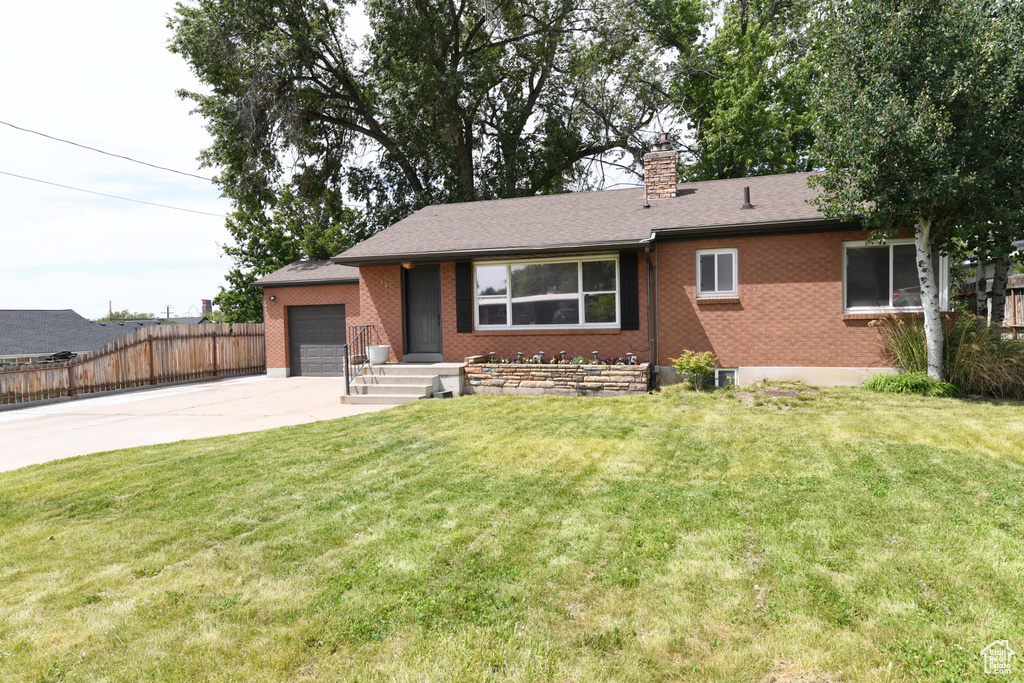 Ranch-style home featuring driveway, an attached garage, brick siding, and a chimney