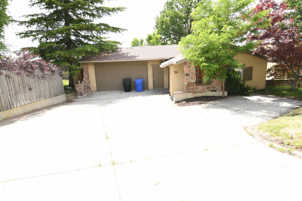 Ranch-style house with stone siding, driveway, stucco siding, a garage, and roof with shingles