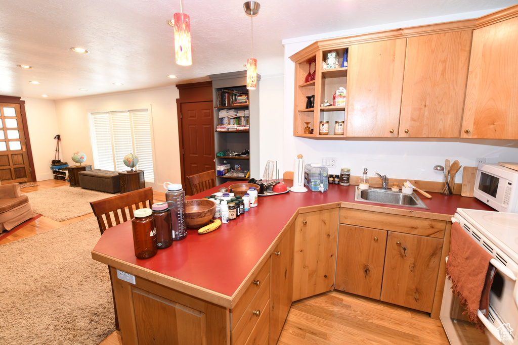 Kitchen with a sink, white appliances, a peninsula, open shelves, and light wood finished floors