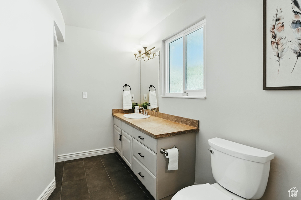 Bathroom featuring vanity, toilet, baseboards, and tile patterned flooring