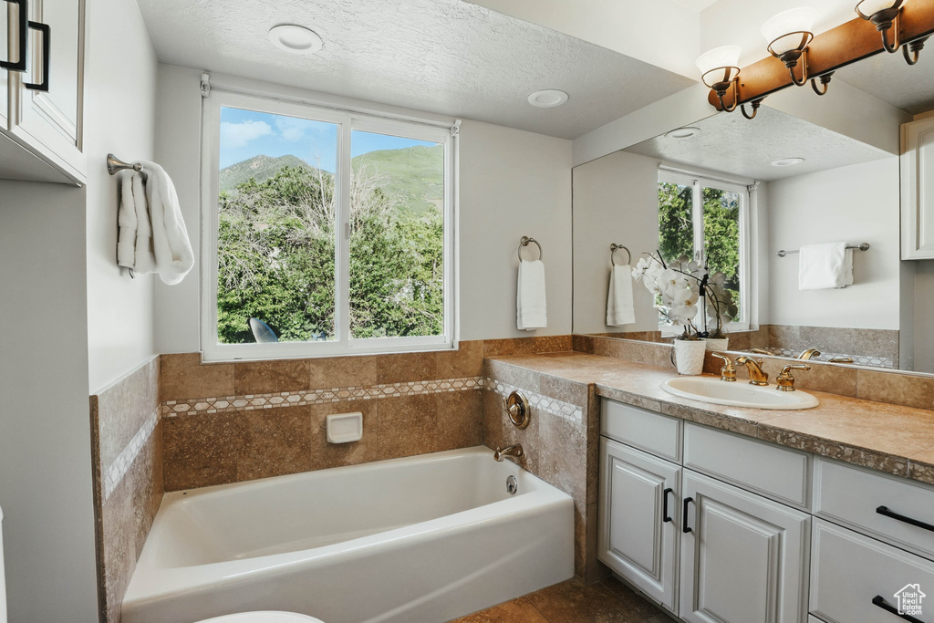 Bathroom with vanity, a garden tub, and a textured ceiling