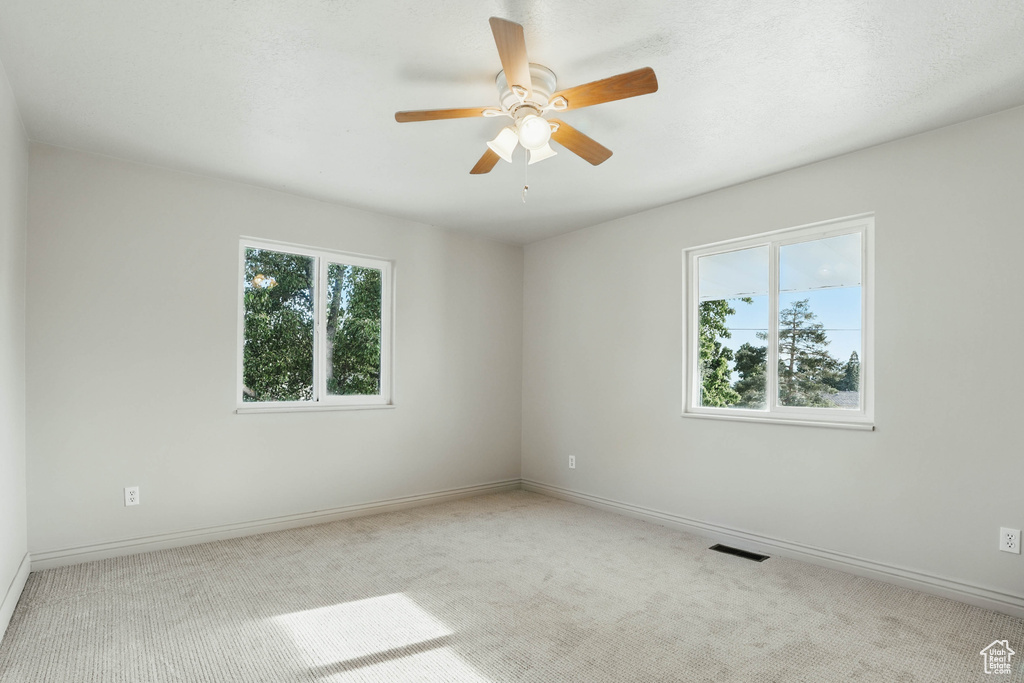 Carpeted spare room with ceiling fan and baseboards