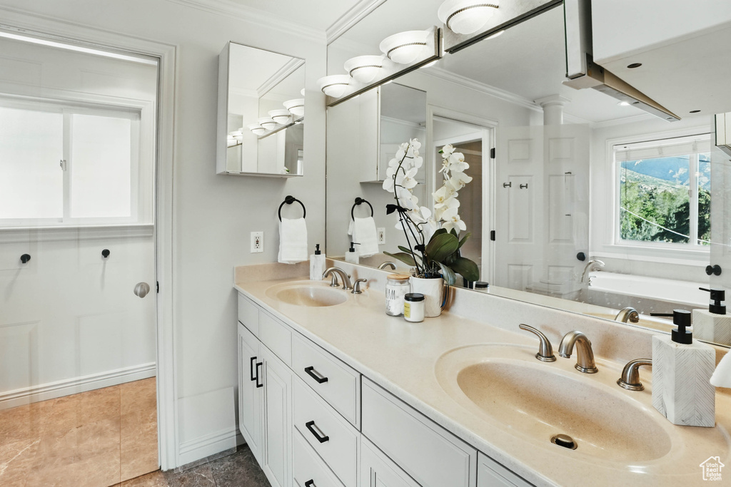 Bathroom with crown molding, double vanity, a garden tub, and baseboards