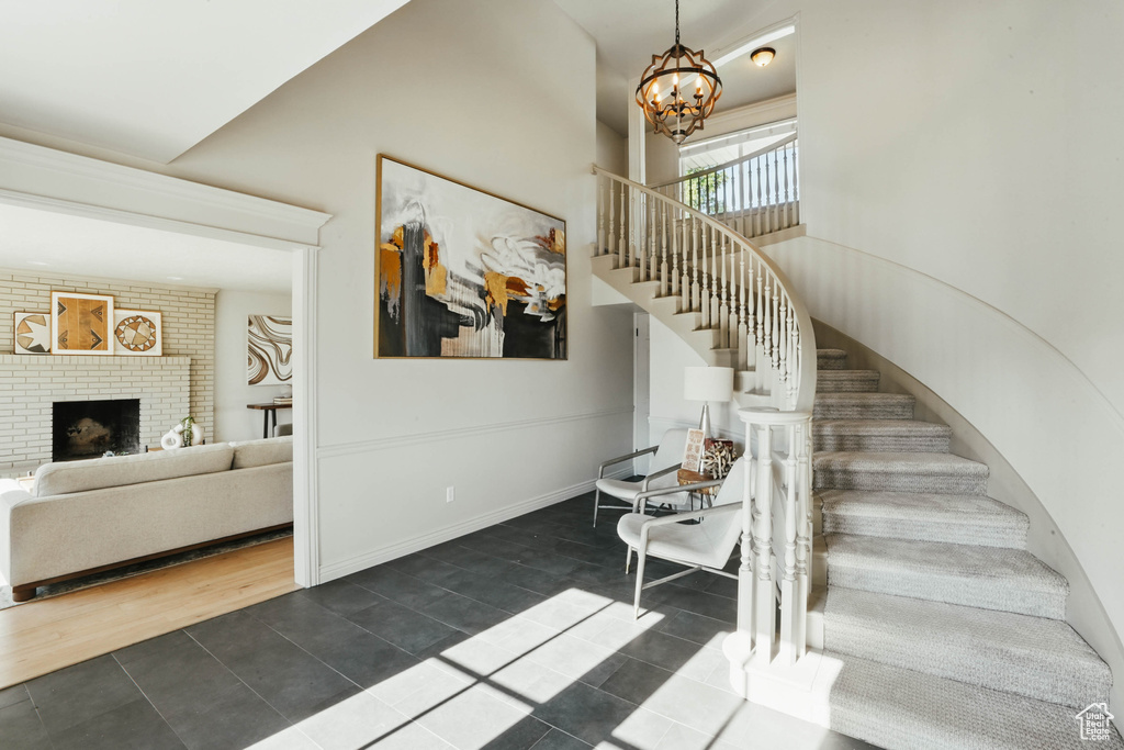 Stairway featuring tile patterned floors, a chandelier, and a fireplace