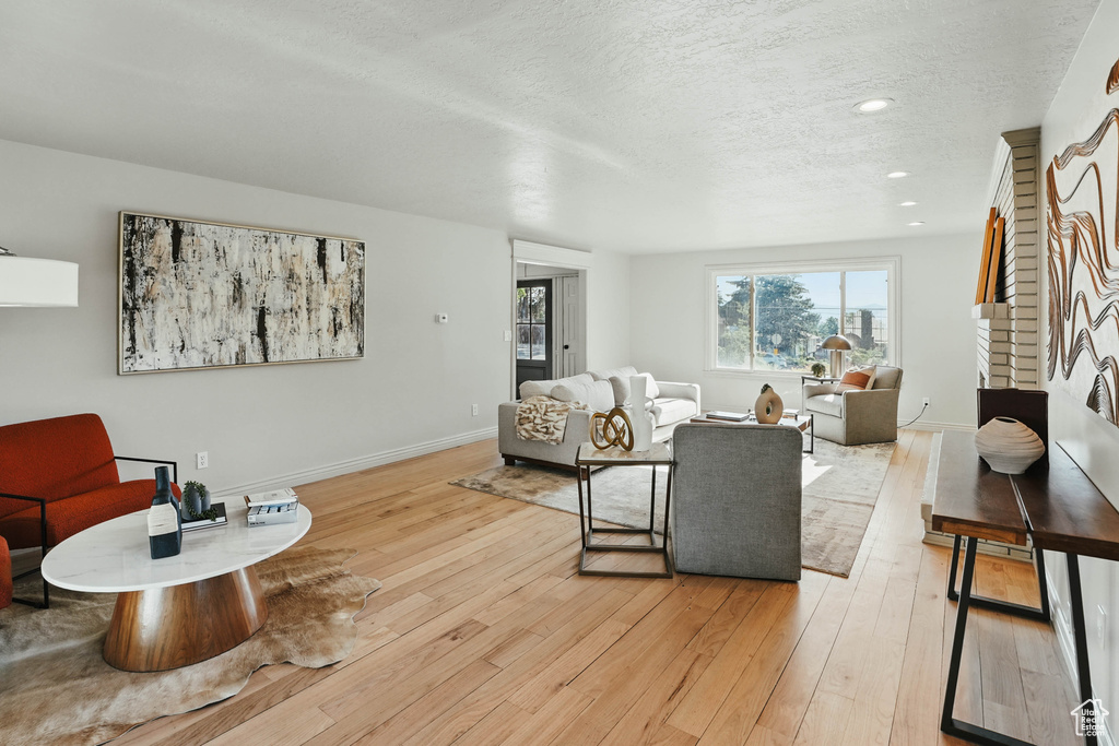 Living room with light wood-type flooring, a textured ceiling, baseboards, and recessed lighting