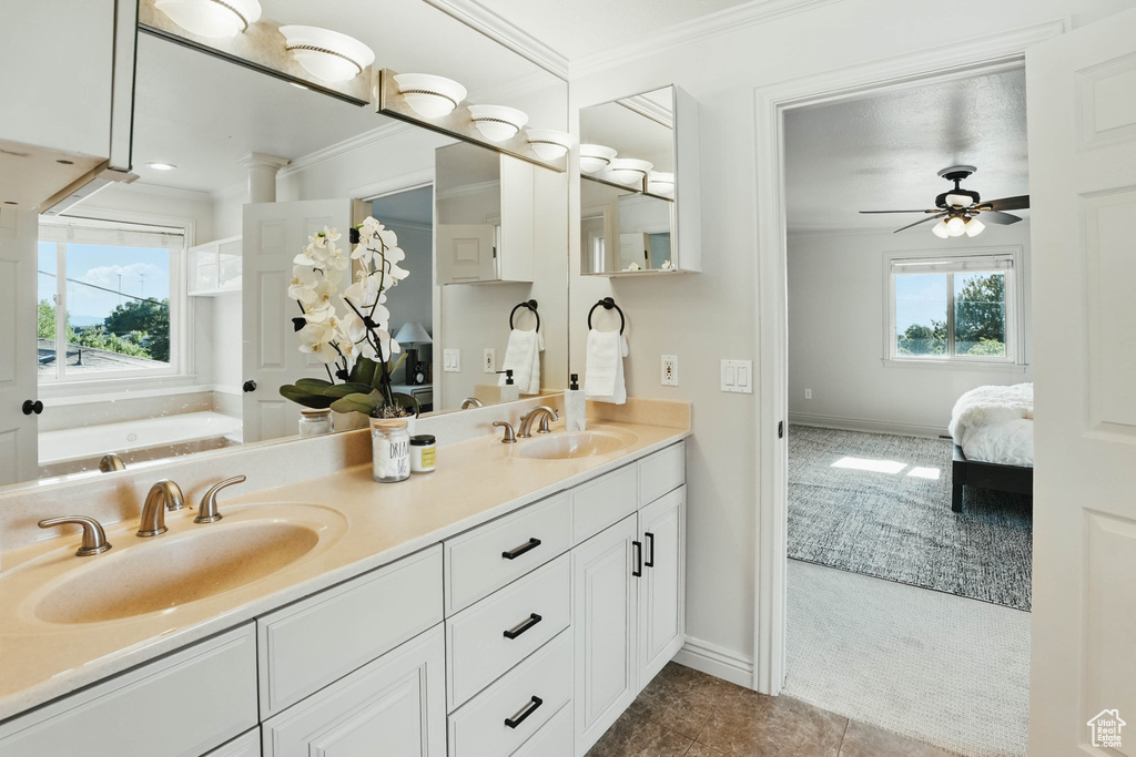 Bathroom featuring ornamental molding, double vanity, ensuite bath, baseboards, and a ceiling fan