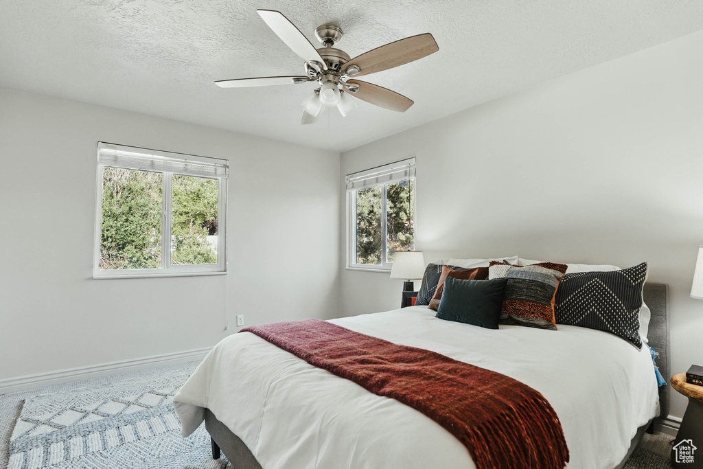 Bedroom featuring multiple windows, baseboards, carpet, and a ceiling fan