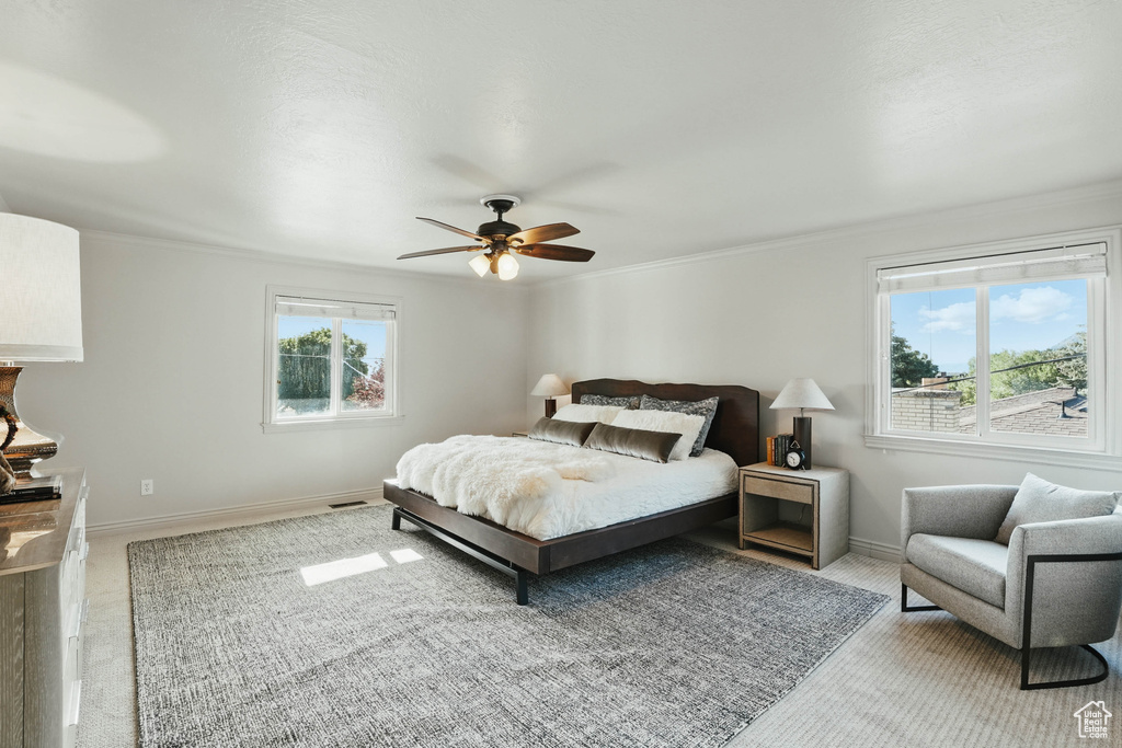 Bedroom featuring light colored carpet, crown molding, baseboards, and a ceiling fan