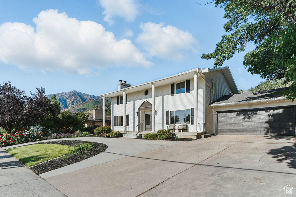 View of front of property with driveway, a chimney, a mountain view, and an attached garage