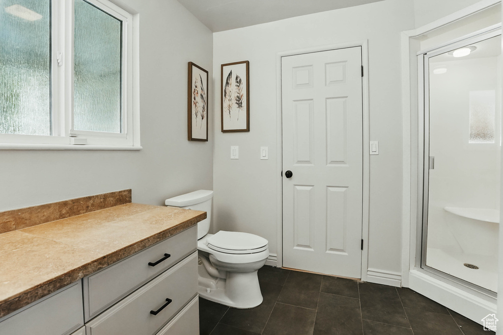 Bathroom with tile patterned flooring, vanity, toilet, and a stall shower