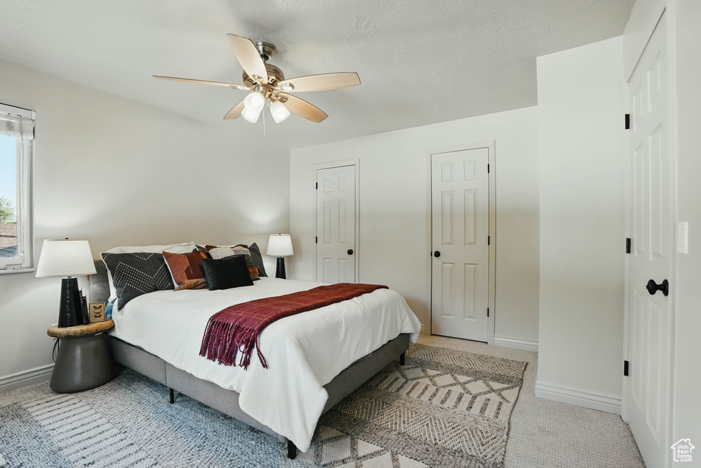 Carpeted bedroom featuring baseboards, ceiling fan, and multiple closets