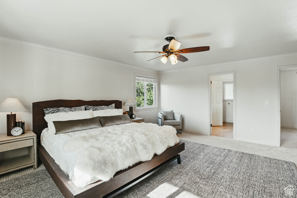 Bedroom with crown molding, light colored carpet, baseboards, and ceiling fan